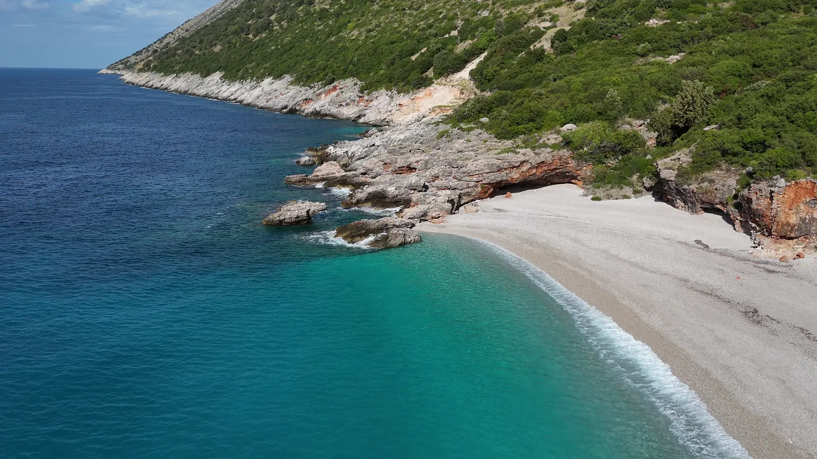 Aerial view of a quiet rocky beach and turquoise water on the Albanian coast